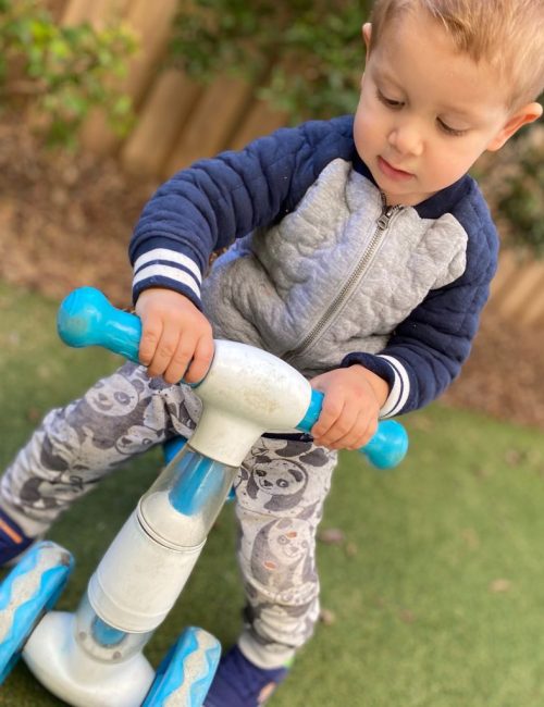 Child playing outdoors on a ride-on toy